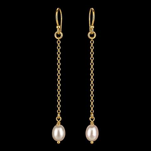 A pair of gold dangle earrings with leverback hooks, short chain links, and a single oval freshwater pearl hanging at the end, set against a solid black background by Judy McPhee of Salt Spring Island.