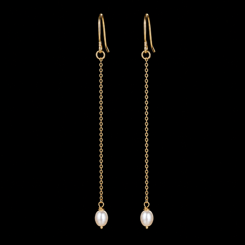 A pair of gold dangle earrings with leverback hooks, delicate chain links, and oval white freshwater pearls, shown against a solid black background by Judy Weeden on Salt Spring Island.