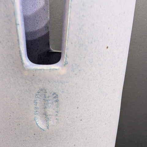 Close-up of a lavender ceramic vase surface with a small water droplet.