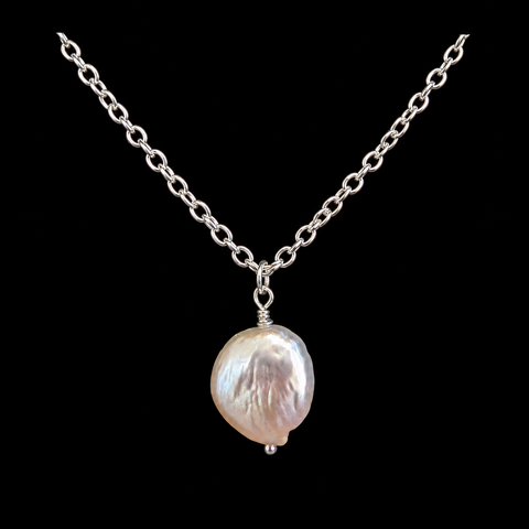 A silver chain necklace featuring a single irregular, lustrous baroque pearl pendant in a silver bezel setting, presented against a solid black background by Judy McPhee of Salt Spring Island.