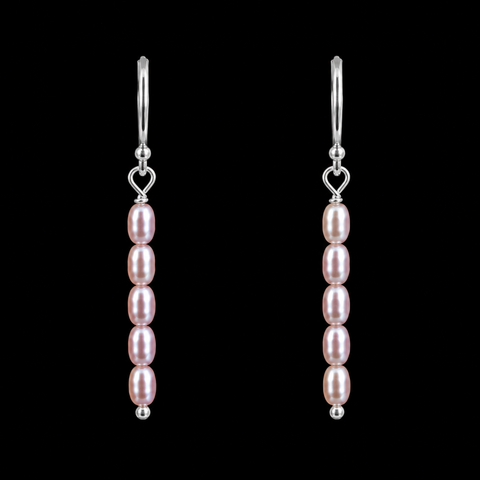 A pair of silver drop earrings featuring five pink freshwater pearls in each earring, suspended from silver fishhook ear wires with a small heart-shaped charm, set against a solid black background by Judy McPhee of Salt Spring island.