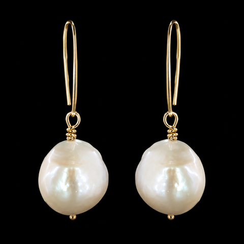 A pair of gold drop earrings featuring irregular, lustrous white baroque pearls, displayed against a solid black background by Judy McPhee of Salt Spring.