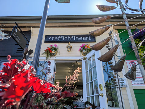 Exterior photograph of steffich fine art gallery on salt spring island featuring beautiful spring plants and wind sculptures