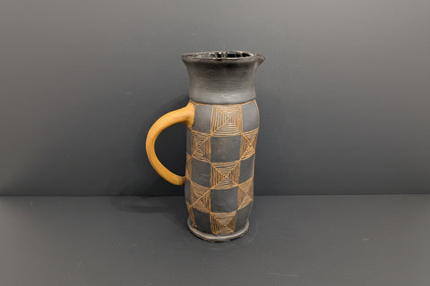 Ceramic mug with geometric patterns and a yellow handle on a gray background