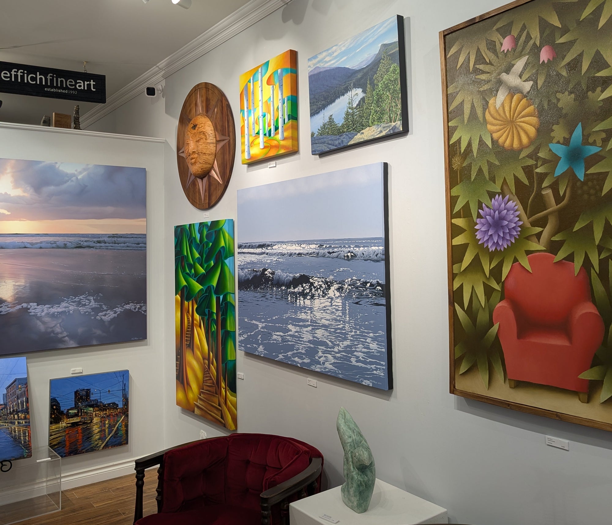 Art gallery with various paintings on the wall and a red chair in the foreground.